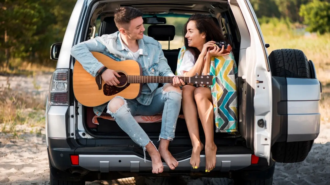 Ganzkörperaufnahme eines Paares, das im Kofferraum sitzt